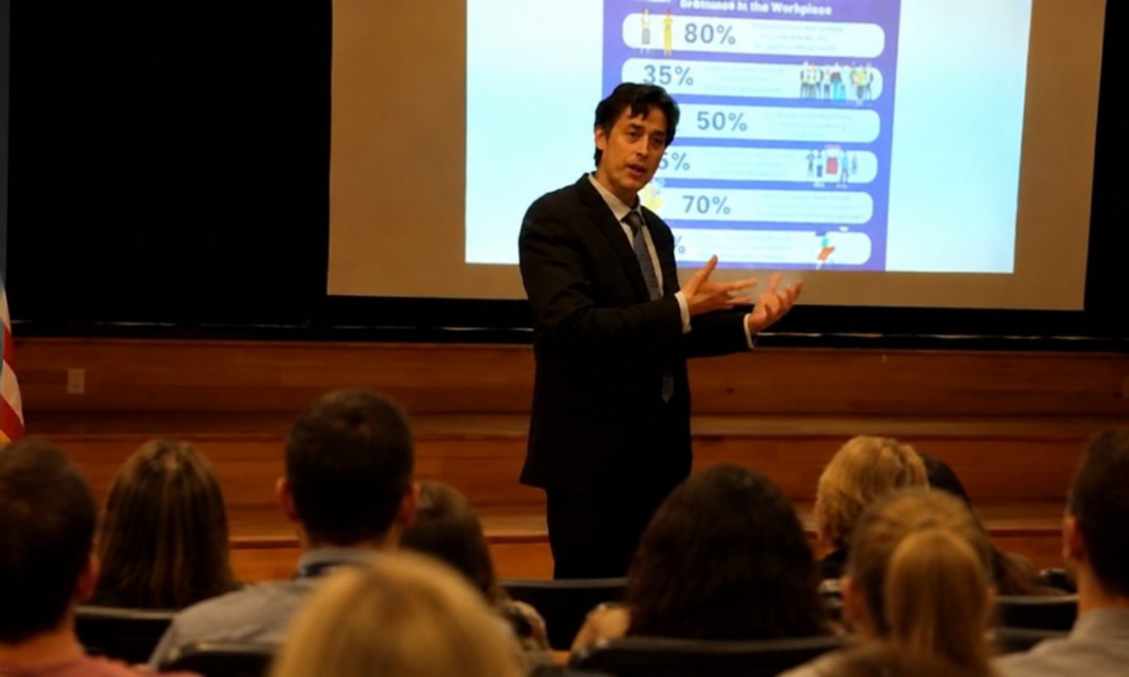 Kenneth Applegate speaking on stage to a seated audience